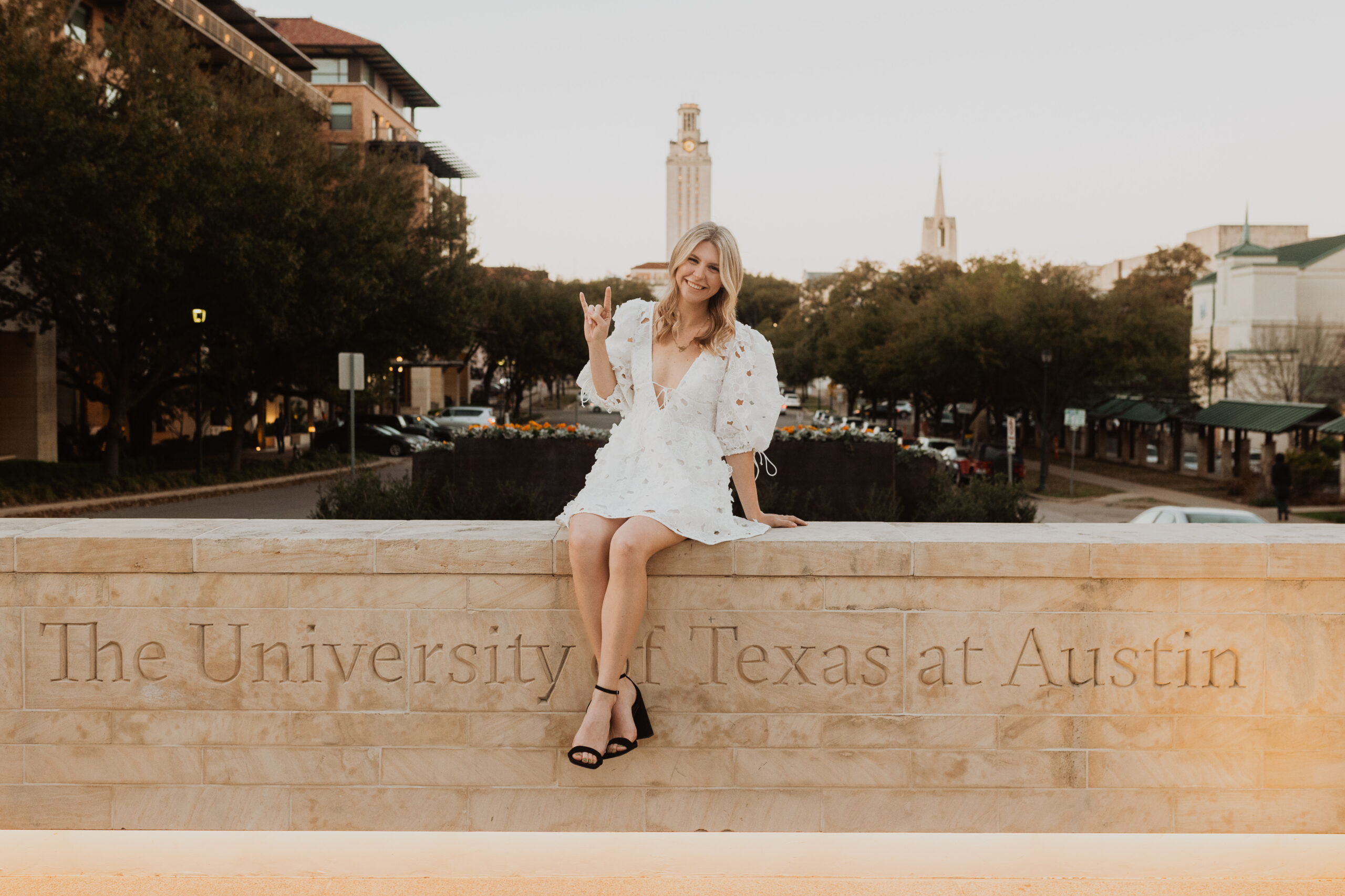 senior at UT Austin taking graduation photos on the sign by MLK