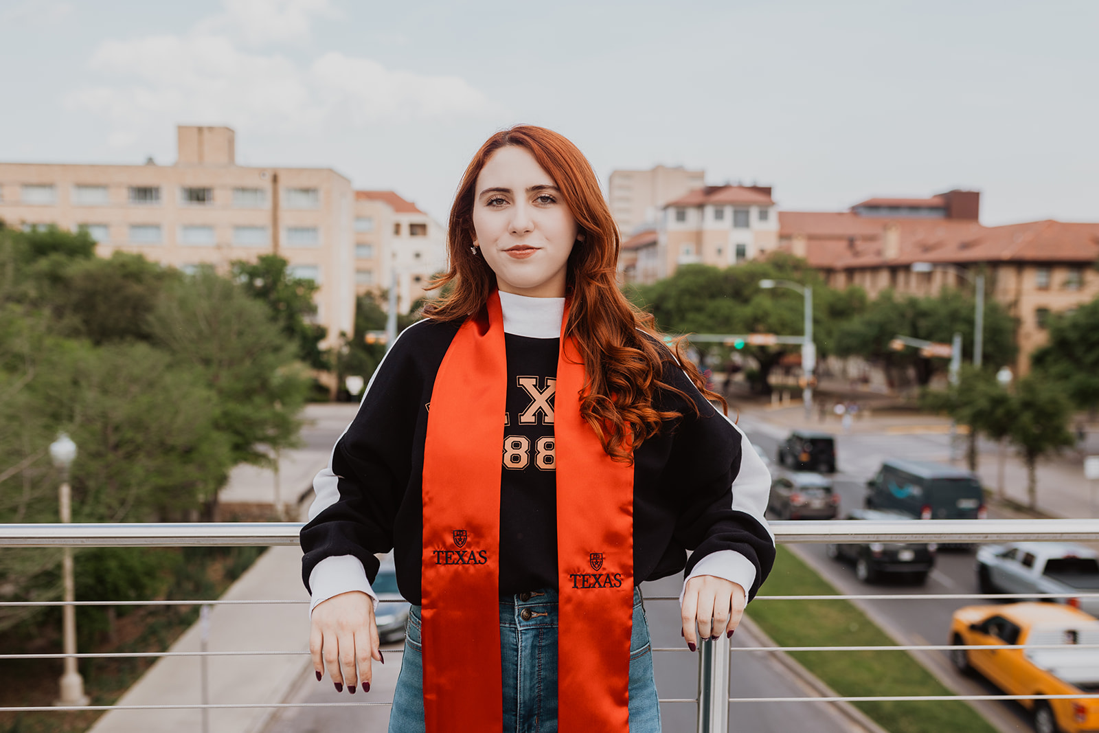 UT Senior posing for photo on the moody pedestrian bridge